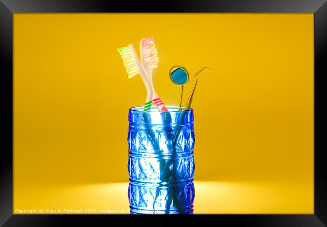 New plastic toothbrushes inside a glass, isolated on bright orange background, with copy space. Framed Print by Joaquin Corbalan