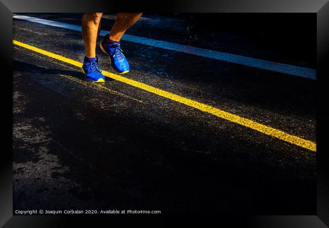 A lonely runner trains on wet asphalt at sunset, copy space. Framed Print by Joaquin Corbalan