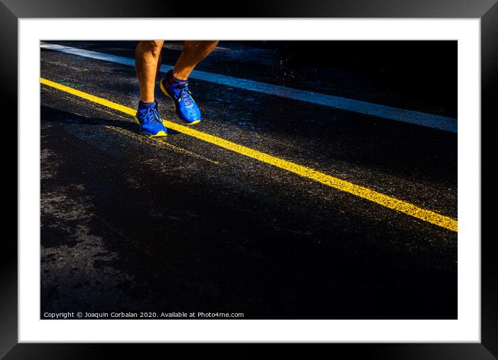 A lonely runner trains on wet asphalt at sunset, copy space. Framed Mounted Print by Joaquin Corbalan