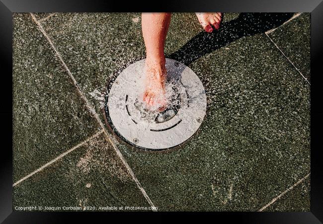 Young barefoot boy running through squirting water in a pool in a spa. Framed Print by Joaquin Corbalan