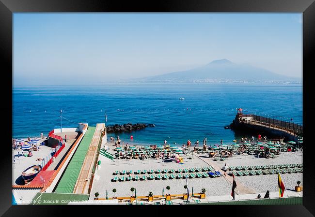  A beach with sunbathers in Sorrento, with background of unfocused view of Vesuvius volcano. Framed Print by Joaquin Corbalan