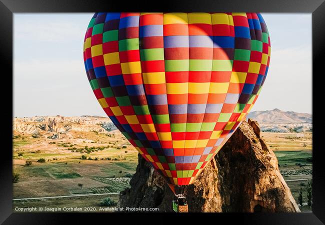 Travelers and tourists flying over mountains at sunset in a colorful aerostat balloon in Goreme, the Turkish cappadocia. Framed Print by Joaquin Corbalan