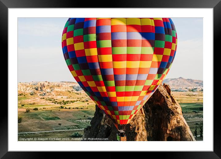 Travelers and tourists flying over mountains at sunset in a colorful aerostat balloon in Goreme, the Turkish cappadocia. Framed Mounted Print by Joaquin Corbalan