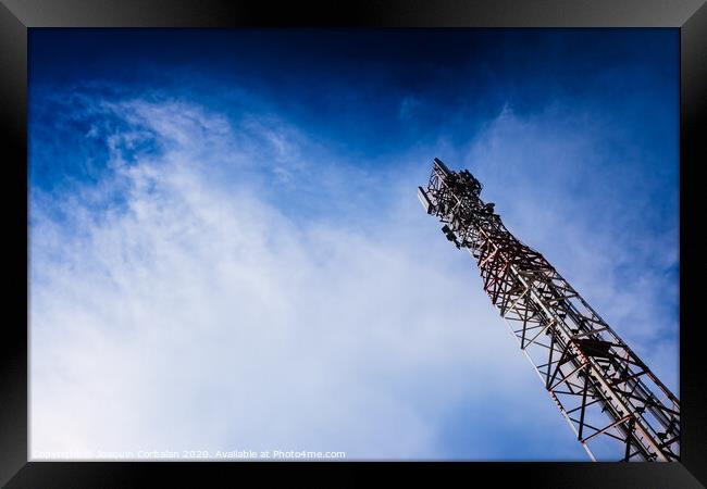A tall modern communications tower provides telecommunications service to a city, negative space on blue background. Framed Print by Joaquin Corbalan