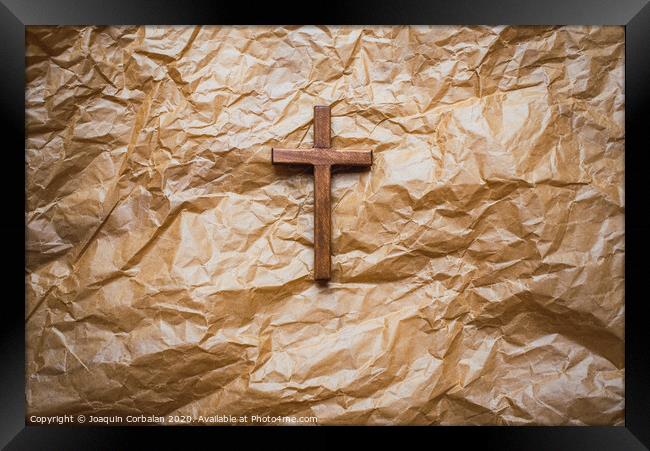 Simple wooden religious cross on brown paper background. Framed Print by Joaquin Corbalan