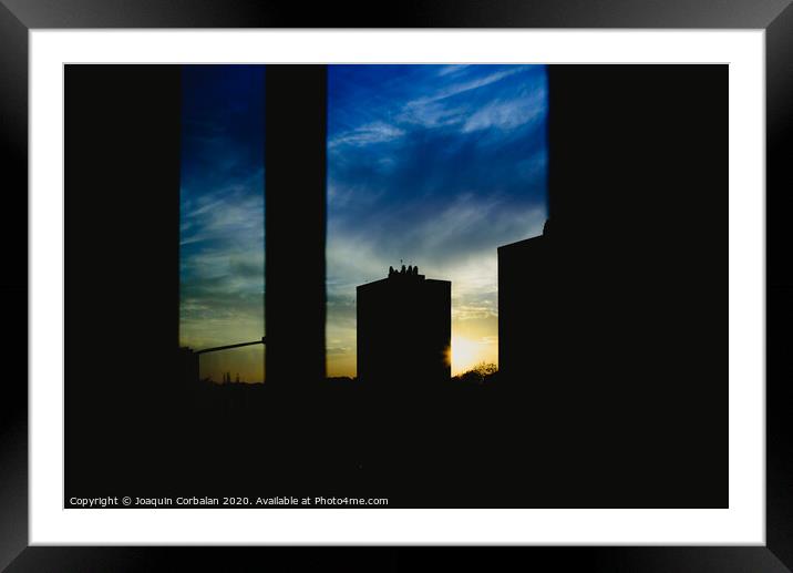 Sunset view from the window of a building, warm and melancholic atmosphere with cloud background. Framed Mounted Print by Joaquin Corbalan