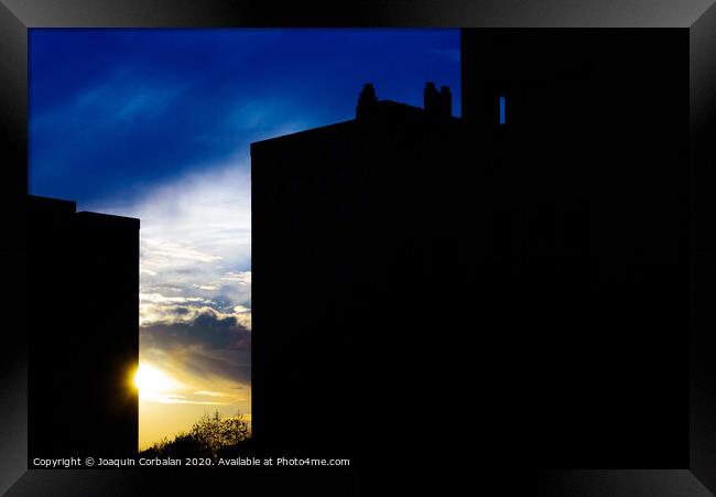 Sunset silhouette in a city with the warm sun behind buildings. Framed Print by Joaquin Corbalan