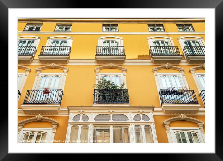 Bright facade of a typical old Mediterranean building painted in bright colors and warm tones. Framed Mounted Print by Joaquin Corbalan