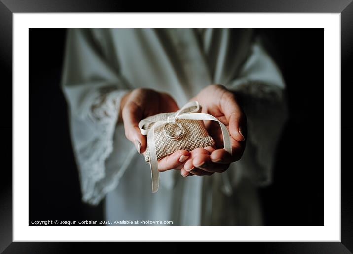 Wedding rings on a pad held by the delicate hands of a bride. Framed Mounted Print by Joaquin Corbalan