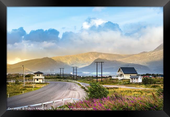 Road with mountains and wooden houses, Leknes. Framed Print by RUBEN RAMOS