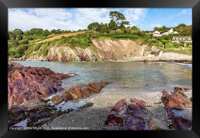 Talland Bay in the sunshine with the coloured red rocks Framed Print by Jim Peters