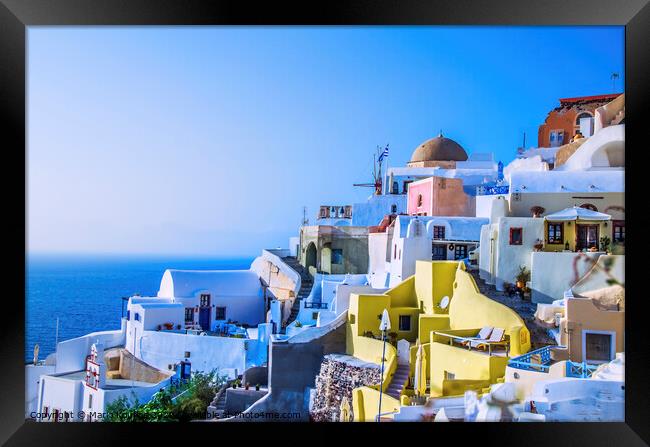 At dusk the sun bathes the traditional and colorful Greek houses in the town of Oia Framed Print by Mario Koufios