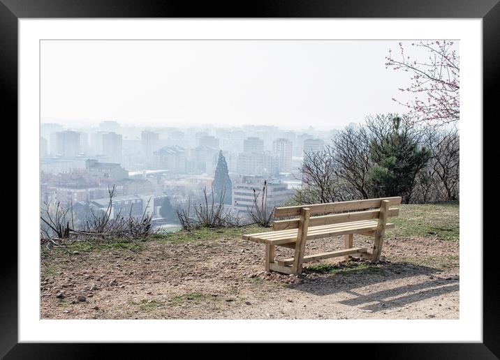 empty wooden bench in spring park over the city Framed Mounted Print by David Galindo