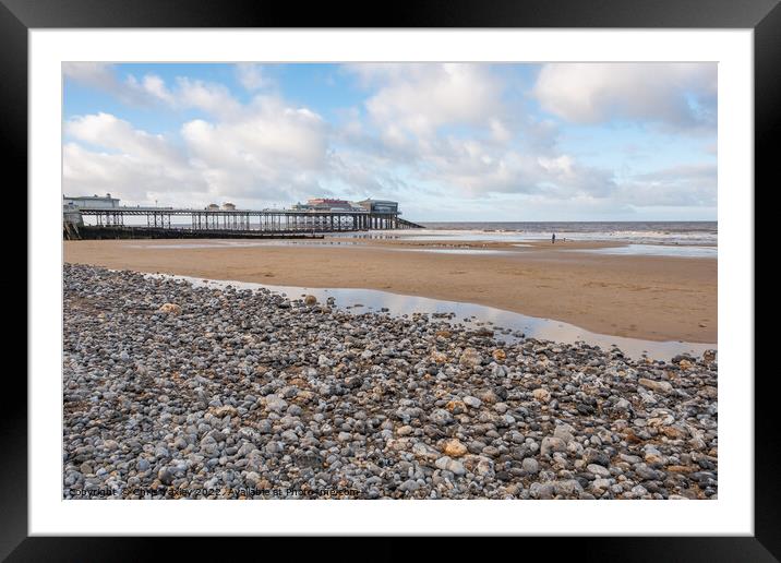 View across a sand and shingle beach with a distant pier in the background Framed Mounted Print by Chris Yaxley