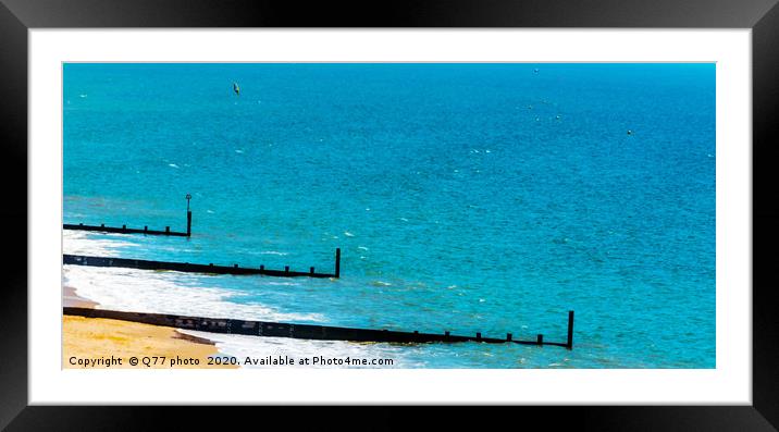 Dock pilings on a sandy beach, blue ocean and yell Framed Mounted Print by Q77 photo