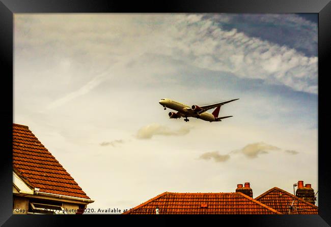 Passenger plane flying over the roofs of residenti Framed Print by Q77 photo
