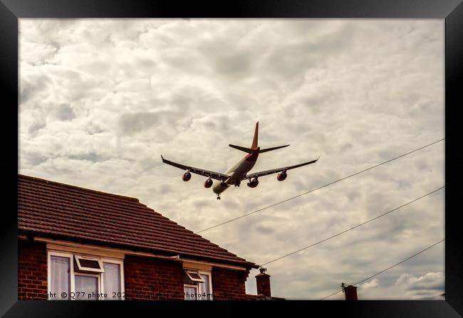 Passenger plane flying over the roofs of residenti Framed Print by Q77 photo