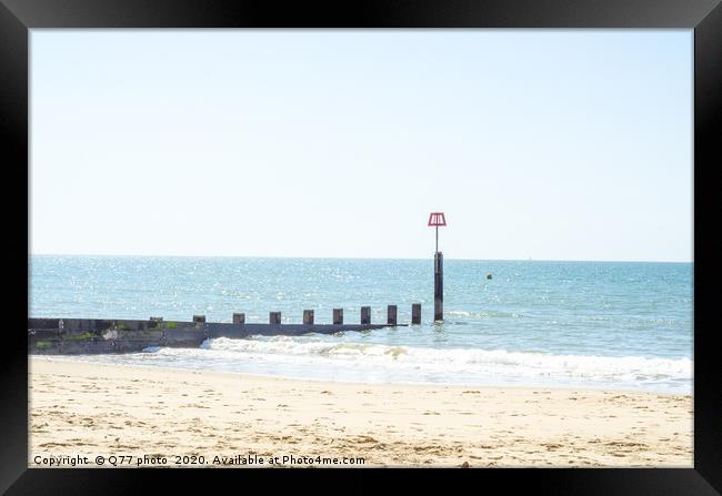 Dock pilings on a sandy beach, blue ocean and yell Framed Print by Q77 photo