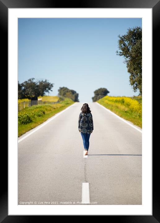 Woman walking on the middle of a road in beautiful yellow flowers landscape in Alentejo, Portugal Framed Mounted Print by Luis Pina