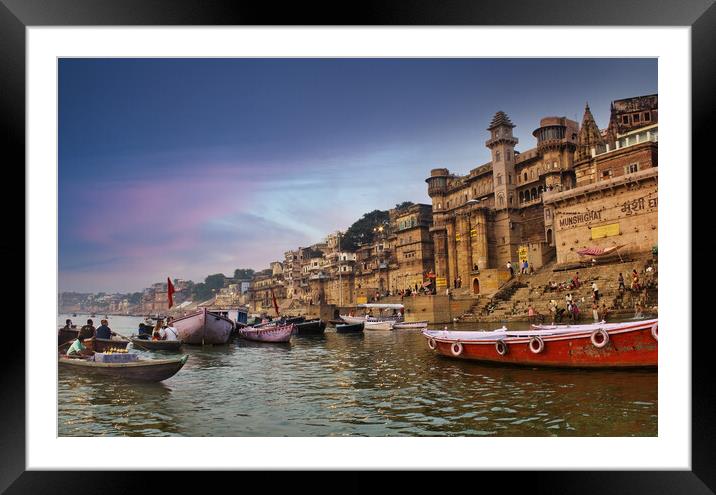 Varanasi, India : People and tourists on wooden boat sightseeing in Ganges river near Munshi ghat against ancient city architecture as viewed from a boat during morning time Framed Mounted Print by Arpan Bhatia