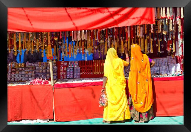 Couple of unidentified women in traditional hindu wear saree buying or shopping jewelery items in the commercial street of Pushkar fair in state of Rajasthan, India. Colorful Indian culture concept Framed Print by Arpan Bhatia