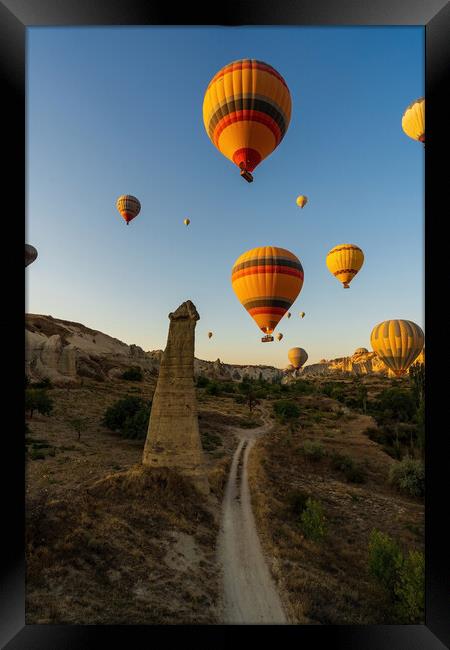 Vertical image of bunch of colorful hot air balloon flying early morning in Cappadocia, Turkey against typical rock formation due to volcanic activity in love valley located in Goreme national park Framed Print by Arpan Bhatia