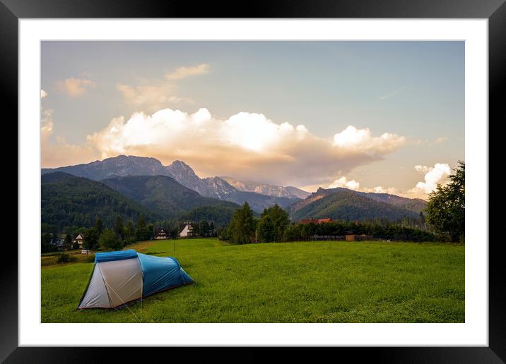 Camping tent put up on green grass meadow field against tatra mountains landscape during sunset sunrise and dramatic clouds, adventure in wild nature concept. Framed Mounted Print by Arpan Bhatia