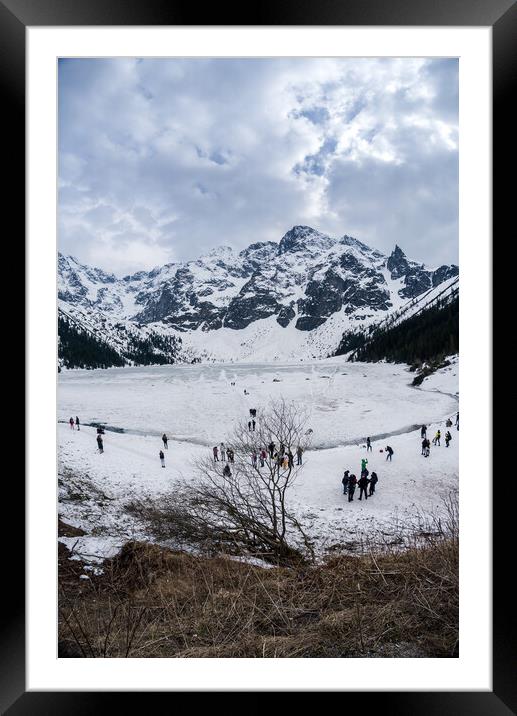 Zakopane, Poland - May 04, 2022: Panorama of Morskie oko frozen lake covered with snowy tatra mountains with people or tourists walking on snow Framed Mounted Print by Arpan Bhatia