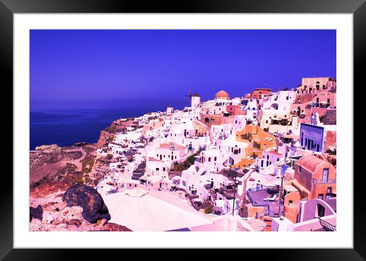 Santorini, Greece: Beautiful city of Oia ( Ia ) on a hill of white houses with blue roof and windmills against dramatic pink sky, located in Greek Cyclades islands in Mediterranean sea Framed Mounted Print by Arpan Bhatia