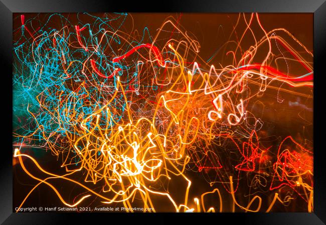 Abstract shapes of glowing swirled neon light Framed Print by Hanif Setiawan