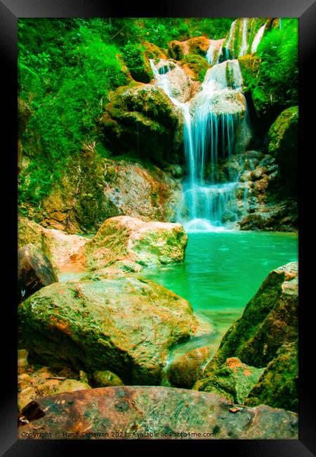 A waterfall flowing over rocks into a lake. Framed Print by Hanif Setiawan