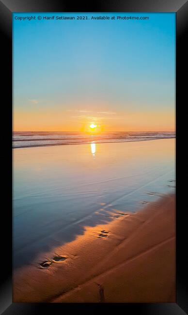 Wide sand beach reflecting orange sunset sunlight. Framed Print by Hanif Setiawan