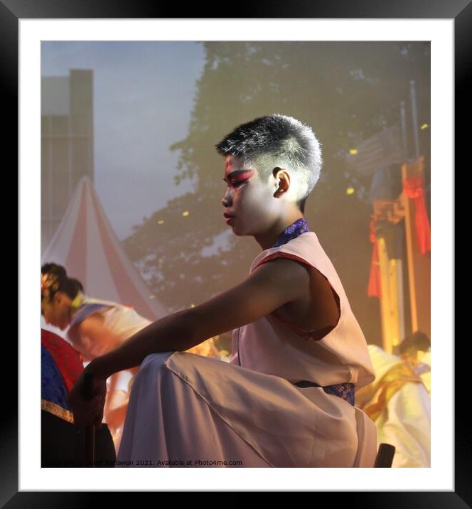 Chinese boy squats down on stage at a festival Framed Mounted Print by Hanif Setiawan