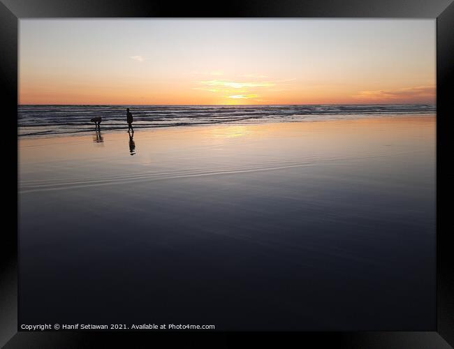 Silhouetted couple enjoys sunset at beach 3 Framed Print by Hanif Setiawan