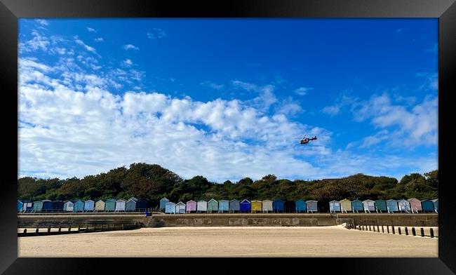 Air ambulance taking off over beach huts at Frinton  Framed Print by Paula Tracy