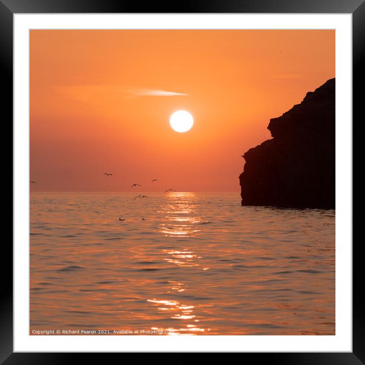 Warm orange sunset reflecting off the sea at South Framed Mounted Print by Richard Fearon