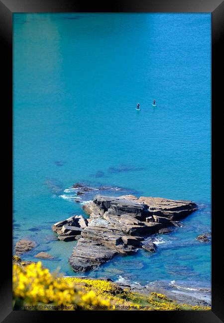 Two paddle boarders on the cornish coastline in pe Framed Print by Peter Barber