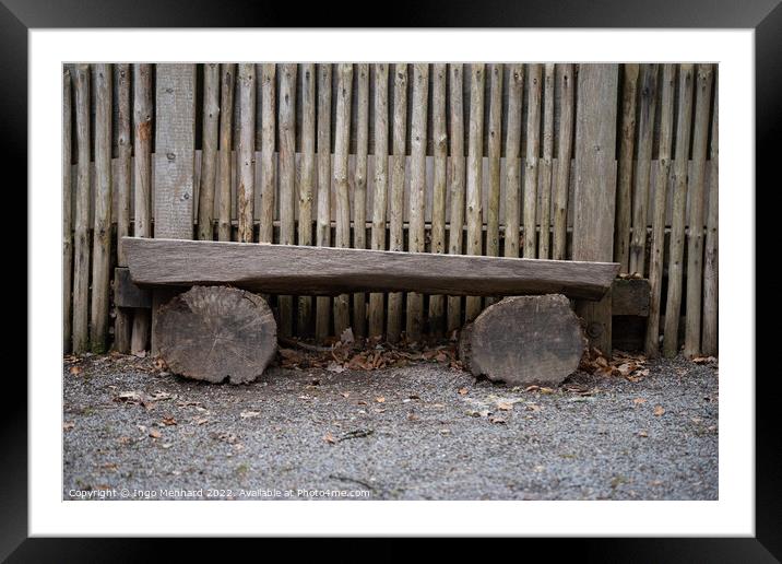 Bench made with logs of wood by a wooden fence Framed Mounted Print by Ingo Menhard