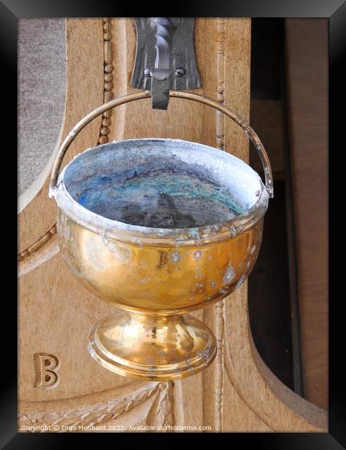 A vertical shot of an old golden goblet hung from a metal hook in the church Framed Print by Ingo Menhard