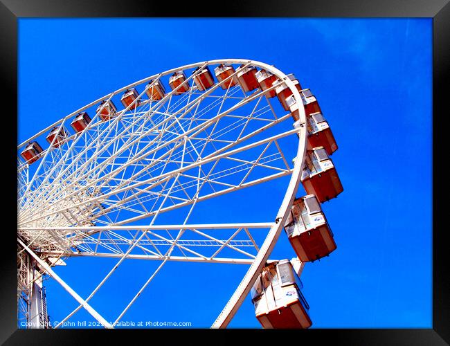 Ferris wheel against a blue sky. Framed Print by john hill