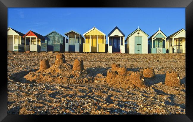A row of beach huts at Thorpe Bay, Essex, UK, with sandcastles on the beach in the foreground. Framed Print by Peter Bolton