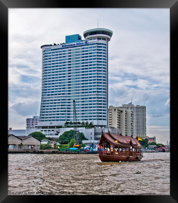 A tourist 'junk' on The Chao Phraya River passes the Millennium Hilton Hotel in Bangkok, Thailand. Framed Print by Peter Bolton