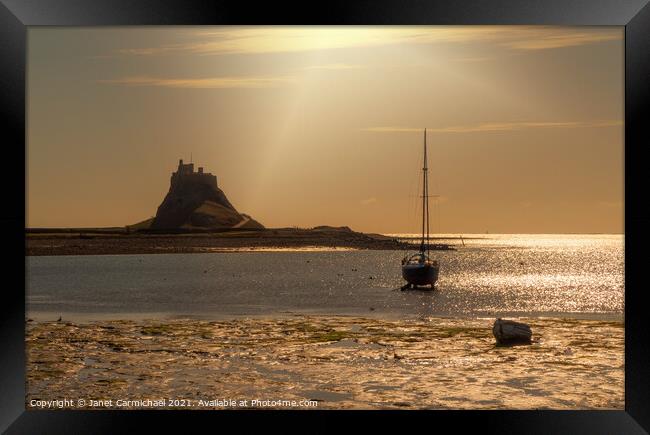 Sunrays on Lindisfarne Harbour and Castle Framed Print by Janet Carmichael