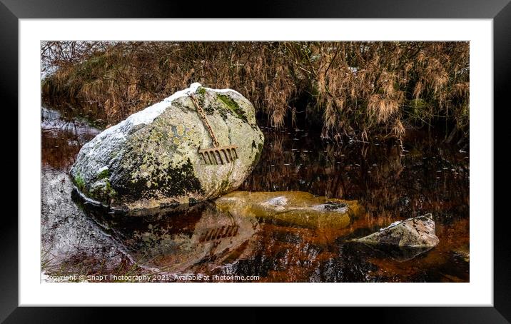 A bronze rake attached to a large boulder by a chain, covered by snow in winter Framed Mounted Print by SnapT Photography