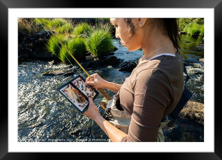 A close up of an asian female selecting fly fishing flies from a box Framed Mounted Print by SnapT Photography