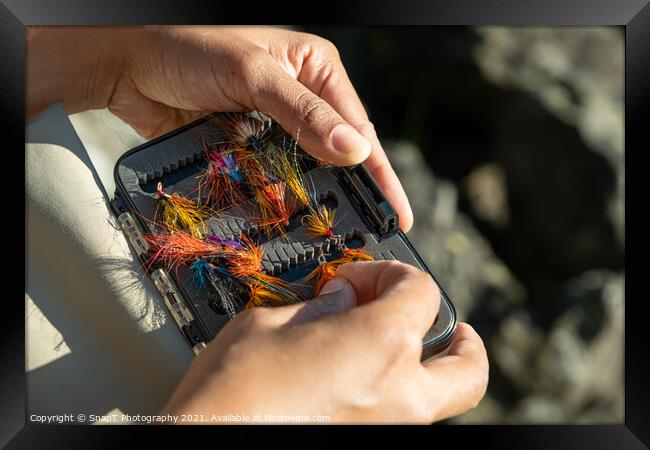 A close up of an asian female selecting salmon fly fishing flies from a box Framed Print by SnapT Photography