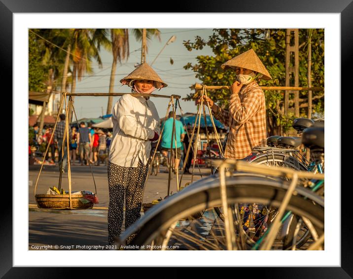Two Vietnamese women with conical hats, carrying shoulder poles by a river in the afternoon Framed Mounted Print by SnapT Photography