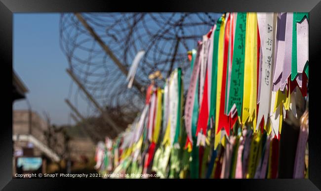 Prayer ribbons attached to a barb wire fence at the Korean Demilitarized Zone Framed Print by SnapT Photography