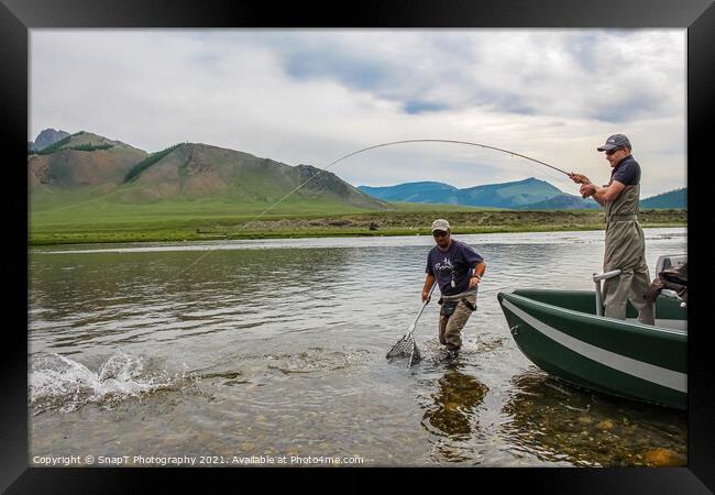 A fisherman with a Taimen Trout on the end of his line in Mongolia, Moron, Mongolia - July 14th 2014 Framed Print by SnapT Photography
