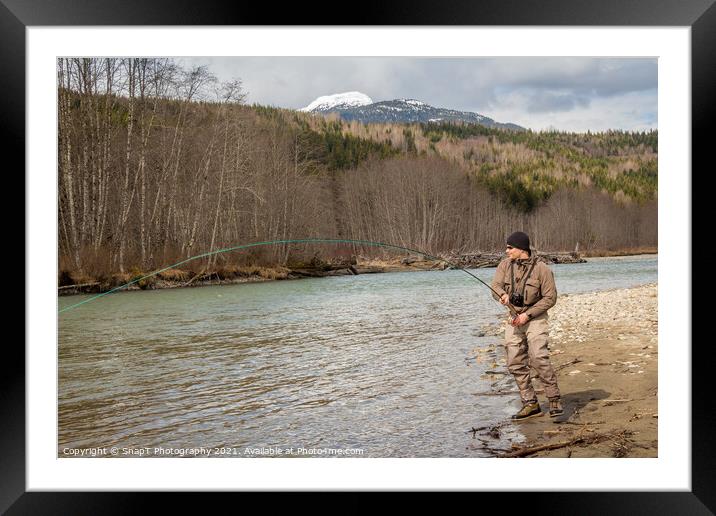 A fly fisherman hooked into a big fish in a river  Framed Mounted Print by SnapT Photography